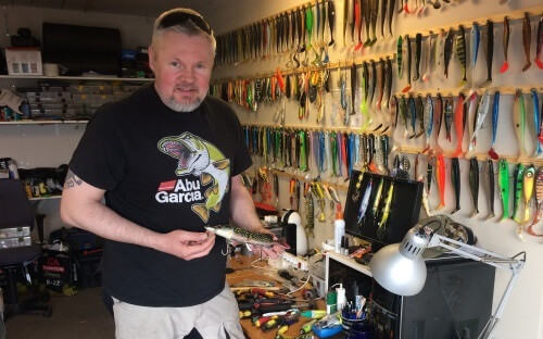 Person som tittar in i kameran och visar sina fiskegrejer i sitt garage