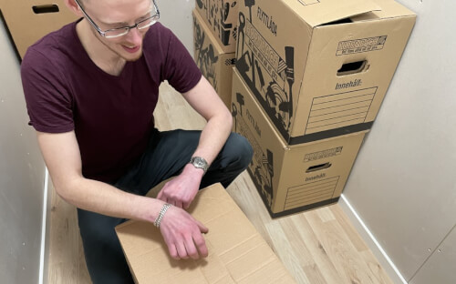 Person med flyttkartonger i förråd